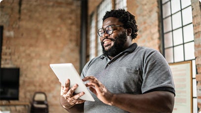 A person using a standing indoors and using a tablet.