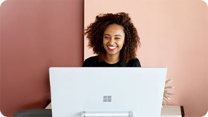 A person sitting in front of a desktop computer and smiling.