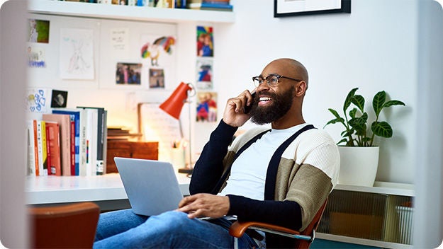 Person using a laptop and phone in a home office.