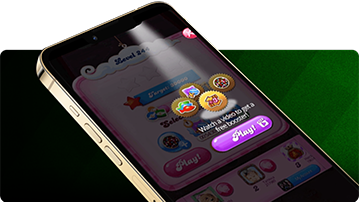 Close-up of a smartphone angled on its side, displaying a Candy Crush game screen with a pop-up offering rewards for watching a video, including colorful badges and a purple “Play” button. The background features green diagonal stripes.