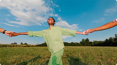 People holding hands outdoors in a grassy field.