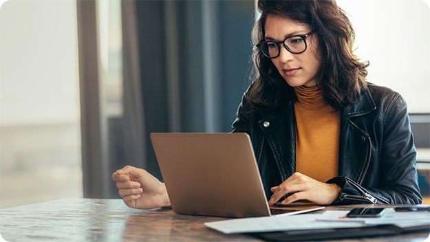 One person sitting indoors at a desk with a laptop computer.