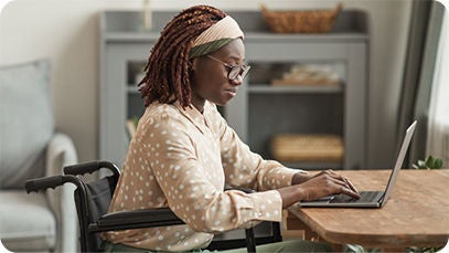 A person in a wheelchair sitting at a desk with a laptop.