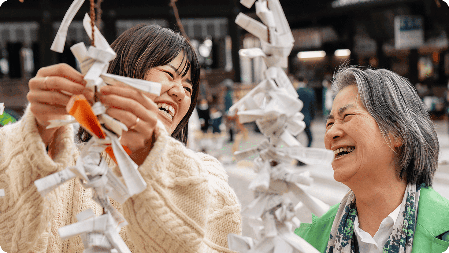 People adding written wishes to a decorative display made of folded paper strips in a public outdoor setting.