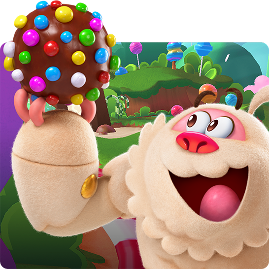 Animated Yeti character from Candy Crush holding a large chocolate ball covered in colorful candy pieces, with a vibrant candy-themed landscape of green hills and lollipop trees in the background.