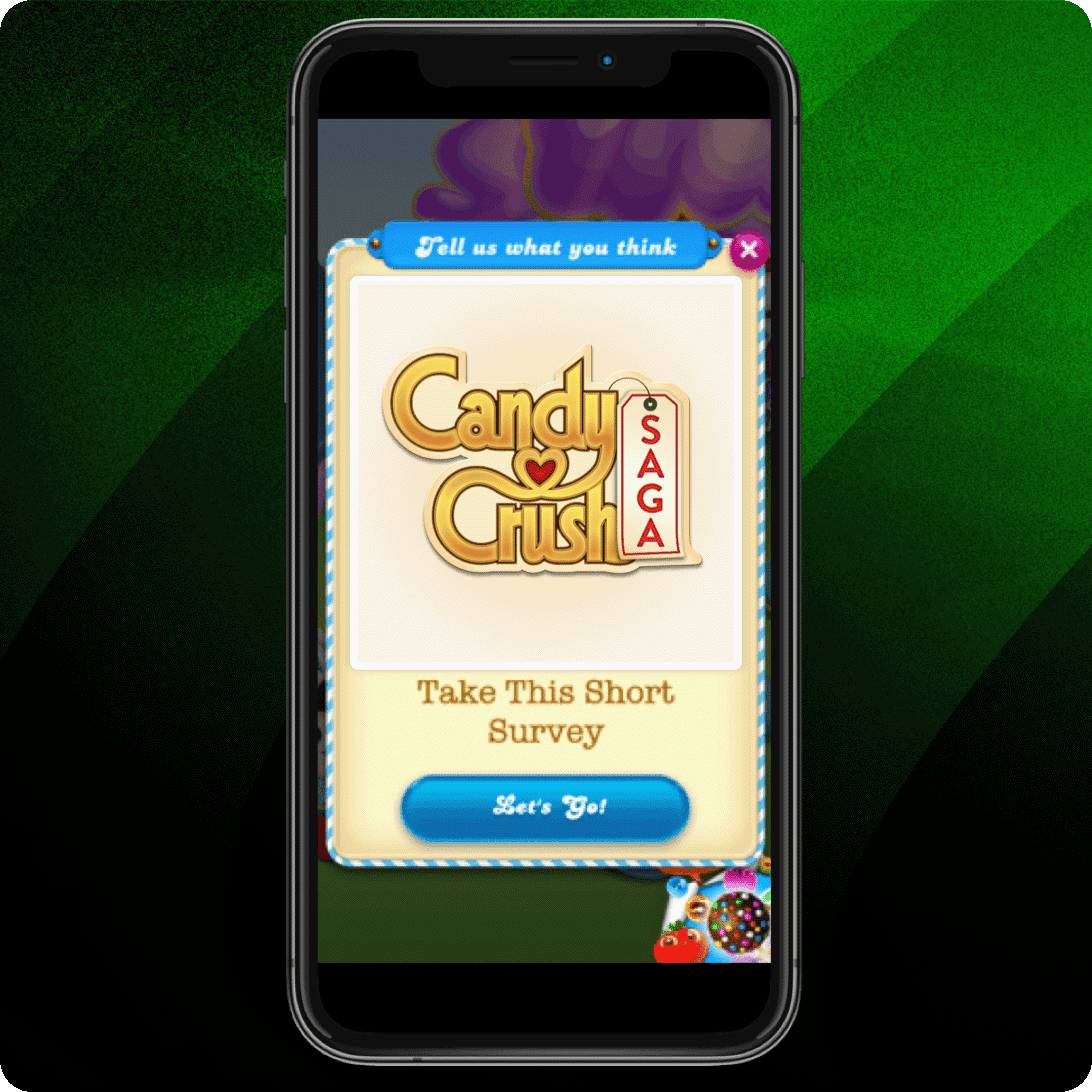 Smartphone displaying a Candy Crush Saga screen with a pop-up message inviting the user to take a short survey, featuring a “Let’s Go!” button at the bottom, set against a green gradient background.