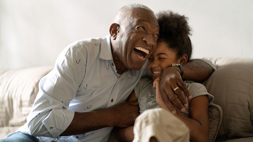 A man and a child hug and laugh together.