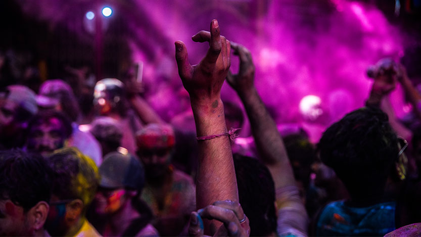 A group of people raise their hands while celebrating in a color festival.