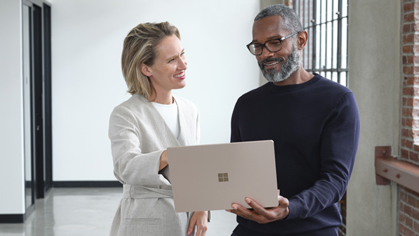 Two smiling people using a laptop.