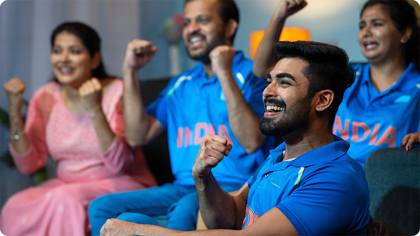 People cheering while watching a sports match at home