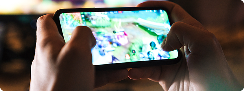 Close-up of a person holding a smartphone and playing a fast-paced mobile game in landscape mode.