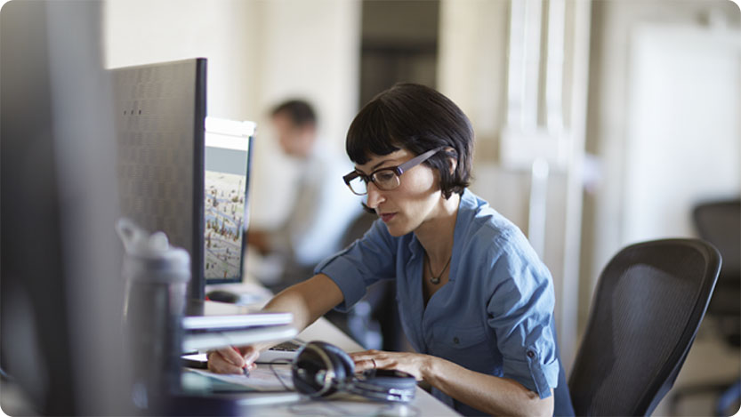 Person working at a desk with a desktop computer in an office setting.