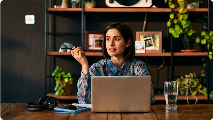 A person indoors sitting at a table with a laptop.