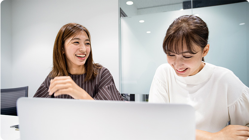 Two people sitting at a desk with a laptop.