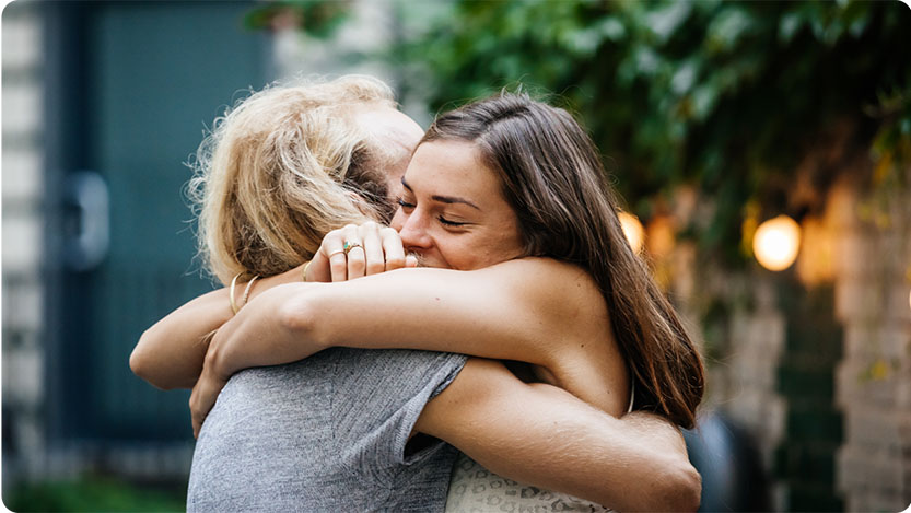 Two people hugging outdoors.