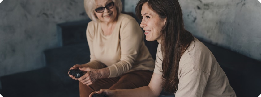 Older and younger individuals smiling while playing a video game with controllers.