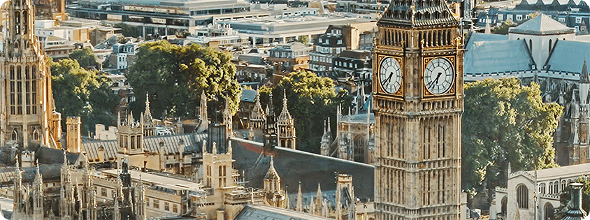 Aerial view of London with Big Ben, surrounded by historic buildings and trees.
