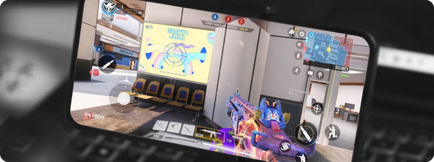 Smartphone mounted on a controller showing a first-person shooter game (Call of Duty: Mobile) in progress.