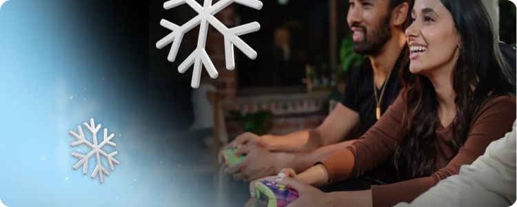 Two people smiling while playing a video game with controllers, with snowflake graphics overlayed