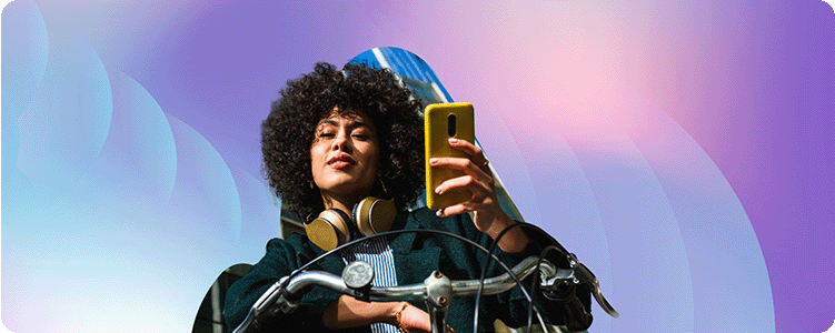 Front image of a person sitting on a bike, holding a cellphone, and looking at the camera.