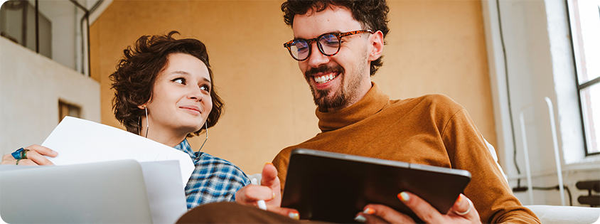  Two people working together, reviewing documents on a laptop and tablet.