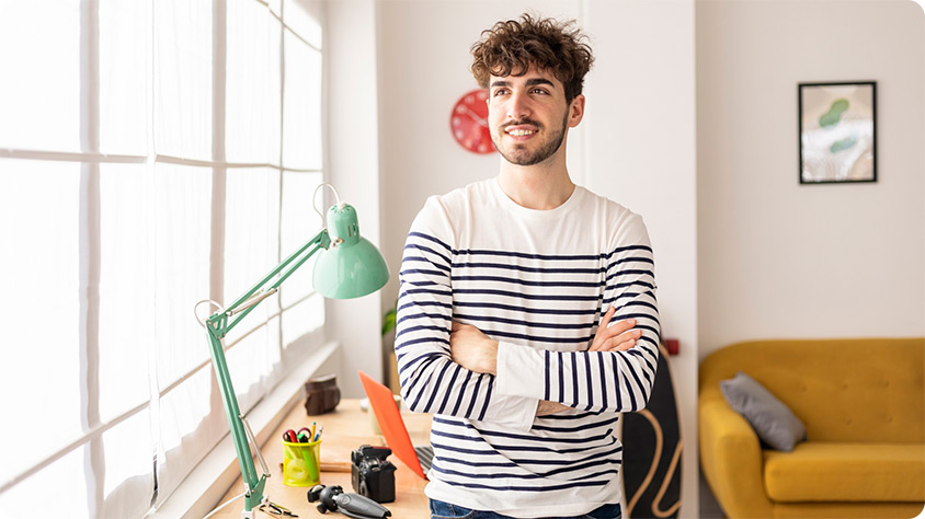 A person standing in a room with arm crossed.