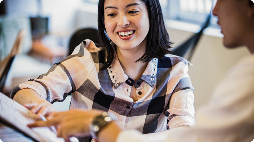 A woman going over her notes with a coworker.