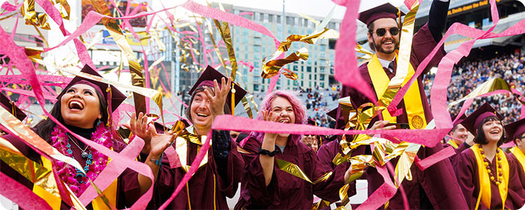 Alumnos universitarios felices celebrando el día de graduación con vestidos de graduación.