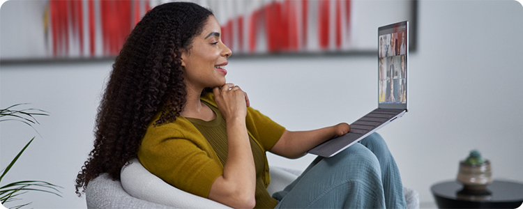 Person with a laptop sitting in an armchair.